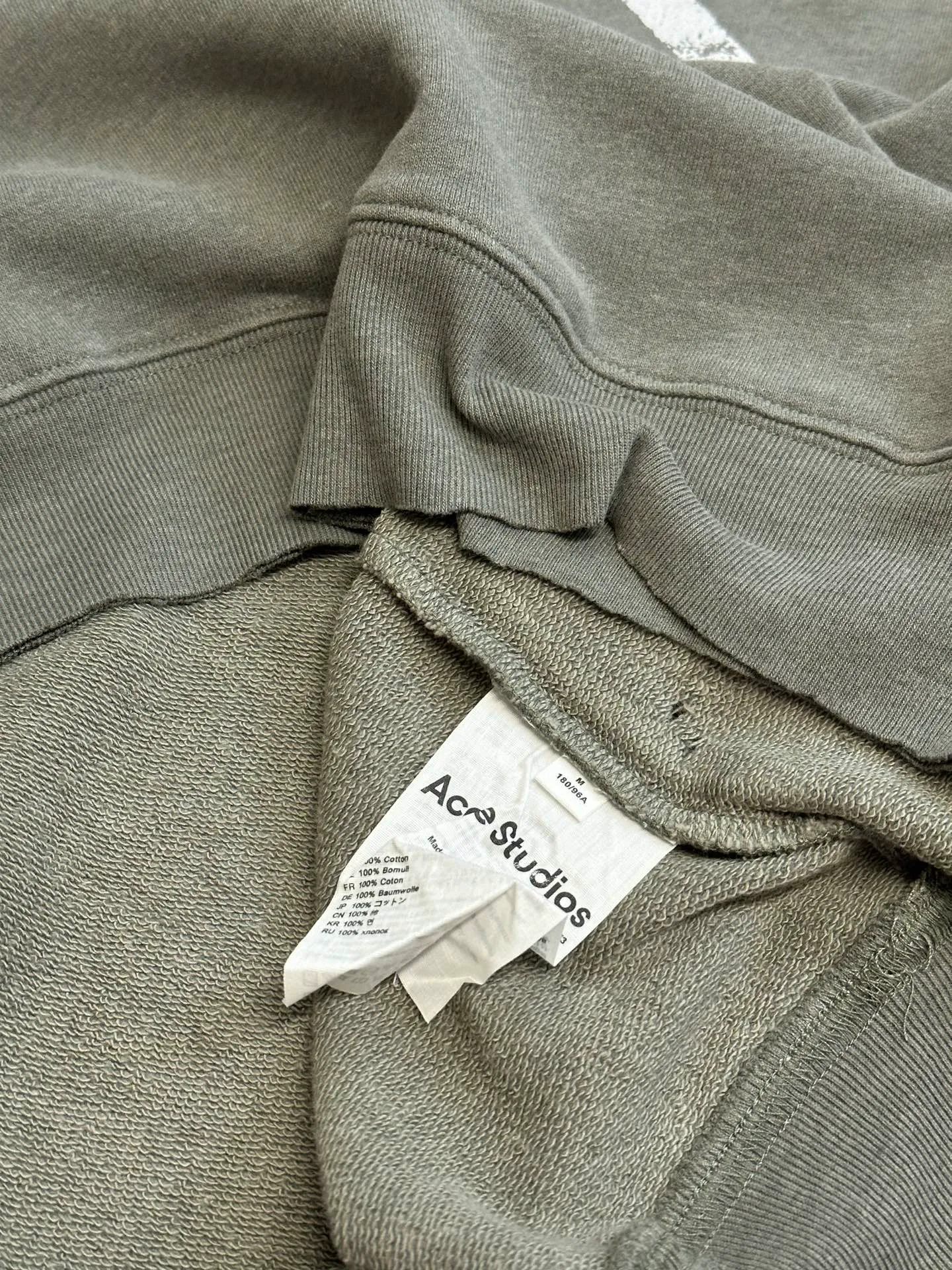 Ac Studios ripped distressed logo sweatshirt, custom dyed 1:1 gray green soft cotton sweatshirt material, the top fabric and terry bottom are the same color configuration, the market fabric In Stock has a different color on the top and bottom, which does not match the original! The minimum order quantity of fabric is 2 tons, and the fabric manufacturing process alone takes 45 days! The unruly soul of Ac Studios is engraved on the chest. The ingenious integration of hole elements and wanton swaying on the Gray canvas is a deliberate rebellion and a break away from the shackles of tradition. It is unique in the wave of the trend. It uses glue printing. The chest printing has been modified three times with the film screen. The glue liquid paint is used to print the pattern on the fabric, and the fabric is baked to fix the printing pattern. Many parts of the body of the garment are frayed and worn at regular intervals by purely artificial means, and marks are manually brushed to add texture and depth to the surface of the garment to imitate the texture of natural wear and tear. size：s m l xl